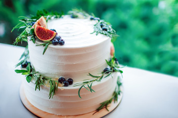 Rustic wedding cake decorated with figs and greenery rosemary.