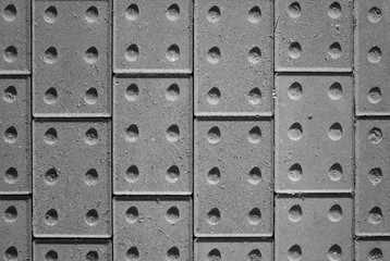 Fototapeta premium Tactile paving bricks with shadow detail photographed and processed in black and white to provide an abstract background