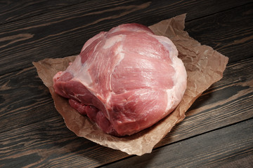 A piece raw pork shoulder. Pork tenderloin on paper on a dark background