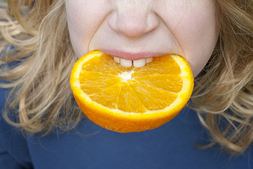 Kind beisst in Orangenscheibe