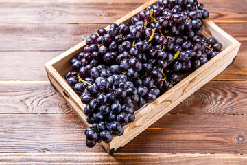 Photo of black grapes in wooden box on table