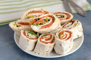 Rolls of thin pancakes with smoked salmon, cream cheese, chives and lettuce.