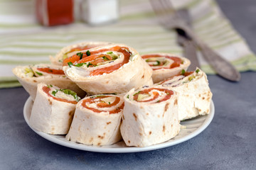Rolls of thin pancakes with smoked salmon, cream cheese, chives and lettuce.