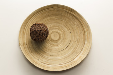 wicker ball on wooden veined plate on top of a table