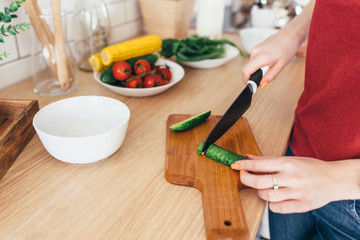 Woman cutting vegetables on the wooden board