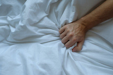 Caucasian man hand grasping on bed