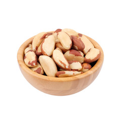 Brazil nut in wooden bowl isolated on white. Side view.