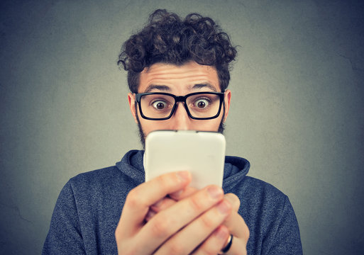 Shocked young man looking at smartphone