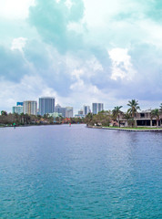 Fototapeta na wymiar Canal of Fort Lauderdale, Florida, USA. Panoramic view of downtown with luxurious estates, palm trees on the waterfront and boats on cloudy day. 