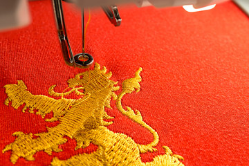 embroidery machine workspace and gold lion design on red fabric