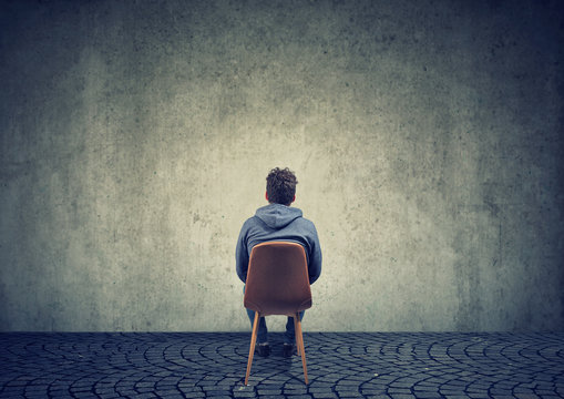 Lonely man on chair against blank wall