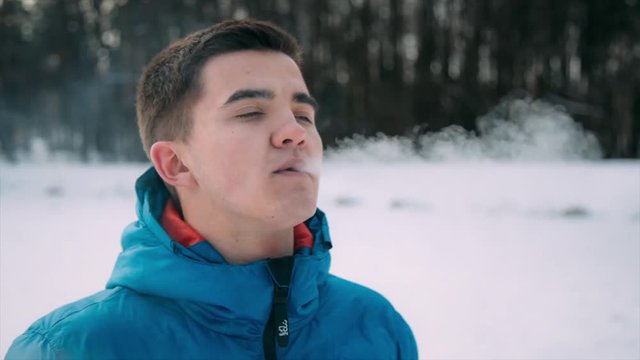 Young boy vaping outside in good sunny winter weather.