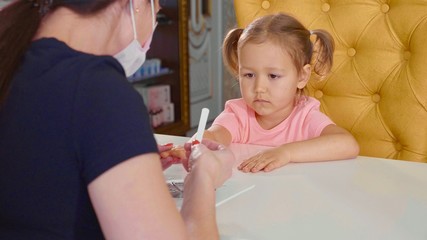 Obraz na płótnie Canvas Beautician doing manicure for little baby girl at beauty spa salon. .