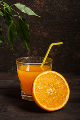 Orange juice in a glass beaker and citrus slices on a dark background with copy space