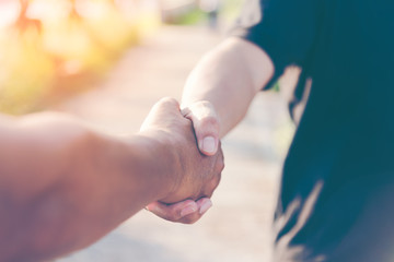 People handshake on outdoors blurred abstract nature background, closeup image. Friends shake hand as a greeting while acccidentally meeting outdoor. Two man handshake as a bussiness agreement.