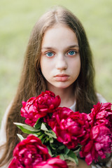 Tender sensitive girl with blue eyes on a picnic with sweet creamy cheesecake with peonies