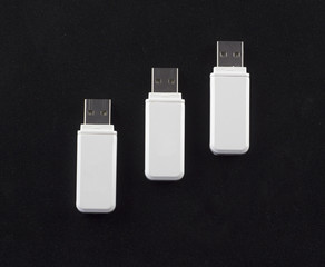 three white flash drives on a black background