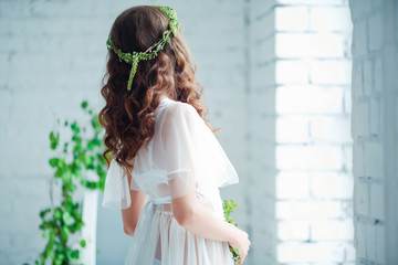 Tenderness and sensuality concept. Beautiful brunette model posing on bed in white lingerie. Sensual portrait of young woman in bedroom. Bottom view