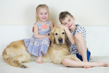 Cute Happy Kids Playing With Golden Retriever Dog On Bed