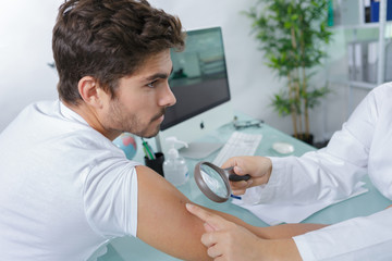 close-up of doctors hands checking mans moles