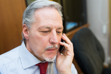 Senior businessman talking on the phone in his office