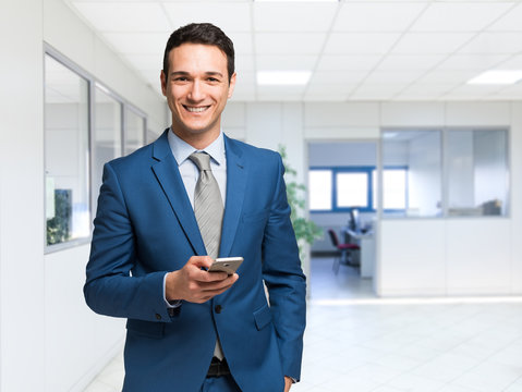 Smiling man using his smartphone in the office