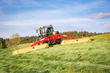 Heuernte - Traktor mit Kreiselmäher-Gespann von hinten im Einsatz
