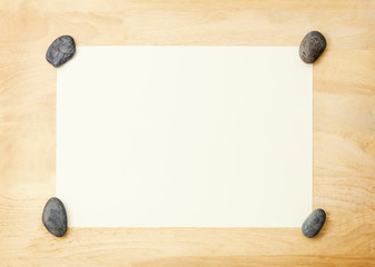 Black Stones placed at the edge of white paper on wood background, Rock Paperweight