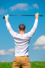 professional golfer rejoices in victory with a raised golf club over his head in the field