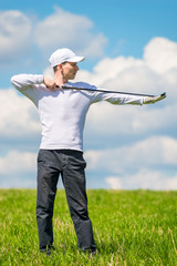 male professional golfer posing with a golf club in a green field on a summer day