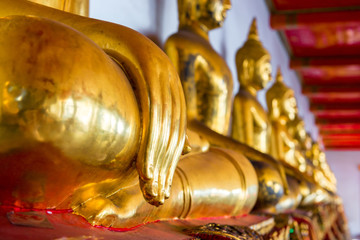 the golden Buddhas sitting in the temple in Thailand