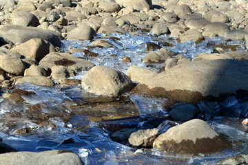 Steine und Eis am Flussufer