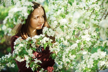 young woman with clean skin near a blooming apple tree. gentle portrait of girl in spring park.