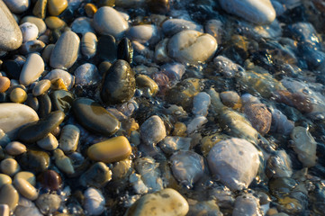 pebble stones on the sea beach, the rolling waves of the sea with foam