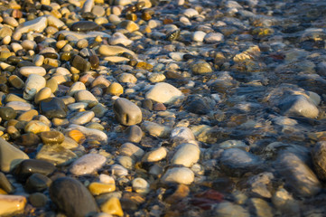 pebble stones on the sea beach, the rolling waves of the sea with foam