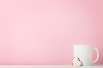 White mug with gingerbread cookie on pink background