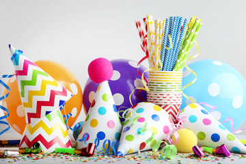 Birthday party caps, blowers and balloons on grey background