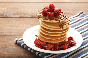 Tasty pancakes with berries and chocolate on wooden table