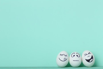 Eggs with funny faces on mint background