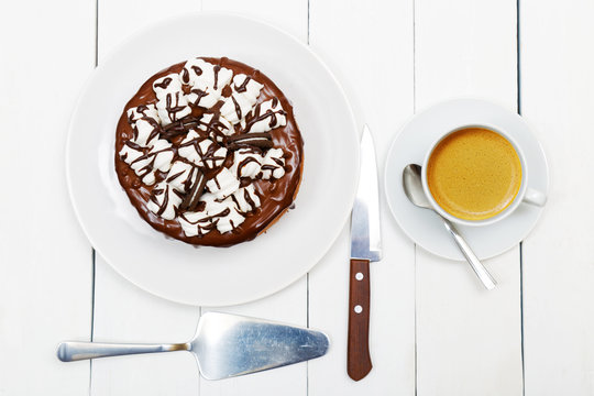 Homemade cake with chocolate souffle decorated with marshmallow and cup of black coffee on white wooden table. Top view.