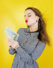 Closeup portrait of a super happy excited successful business woman, funny looking face, holding money dollar bills in hand, isolated yellowphone. Positive human emotions, a sense of expression.