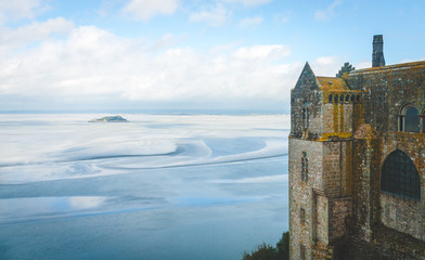 Scenic view on small Tombelaine tidal island and fragment of abbey on Le Mont Saint-Michel island famous for low tides in Normandy, France