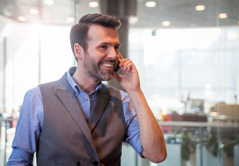 Handsome businessman talking phone in modern indoors, success in business