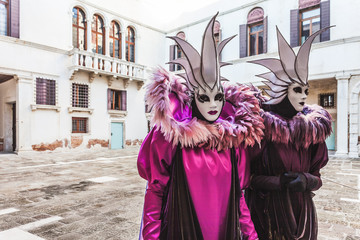 Obraz premium VENICE, ITALY - FEBRUARY 10 2018: Pair of white and purple colored carnival masks inside a small courtyard