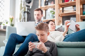 Family with laptop, tablet and smartphone, everyone using digital devices - Powered by Adobe