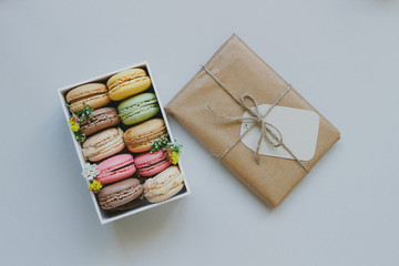 Cute gift box with delicious colorful macaroons on the light blue background, top view