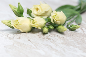 Bunch of white Eustoma on light wooden background with copy space. Floral greeting card.
