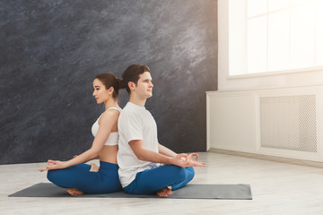 Fototapeta na wymiar Young couple meditating together, back to back