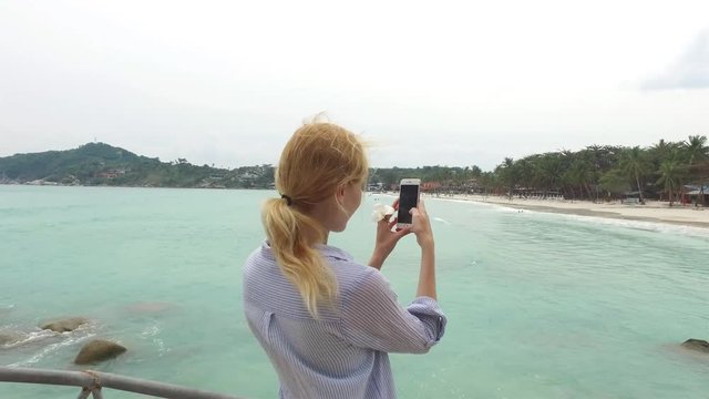 girl is taking pictures on the phone of a tropical island