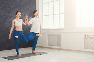 Couple training yoga in balance pose.